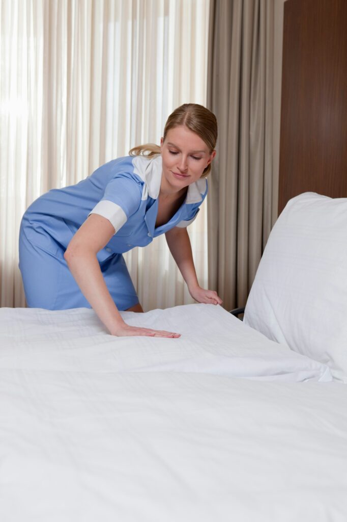 room maid making a bed in hotel room